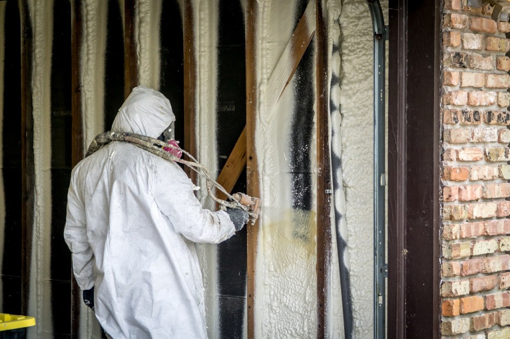 Worker spraying closed cell spray foam insulation on a home that was flooded by Hurricane Harvey